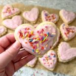 close up of sourdough sugar cookie cut into a heart with pink frosting and sprinkles